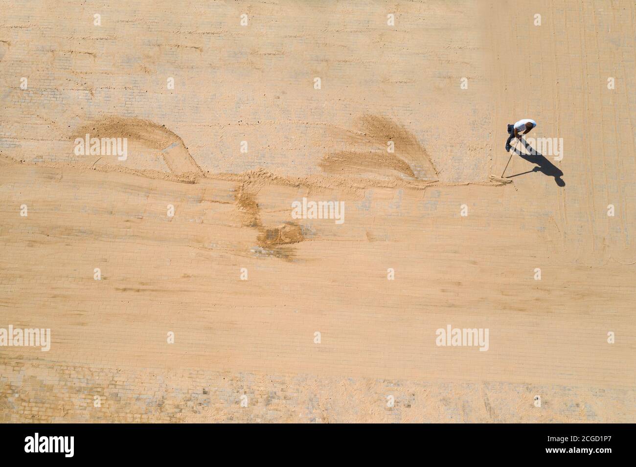 Pavement construction worker filling the block joints with sand using