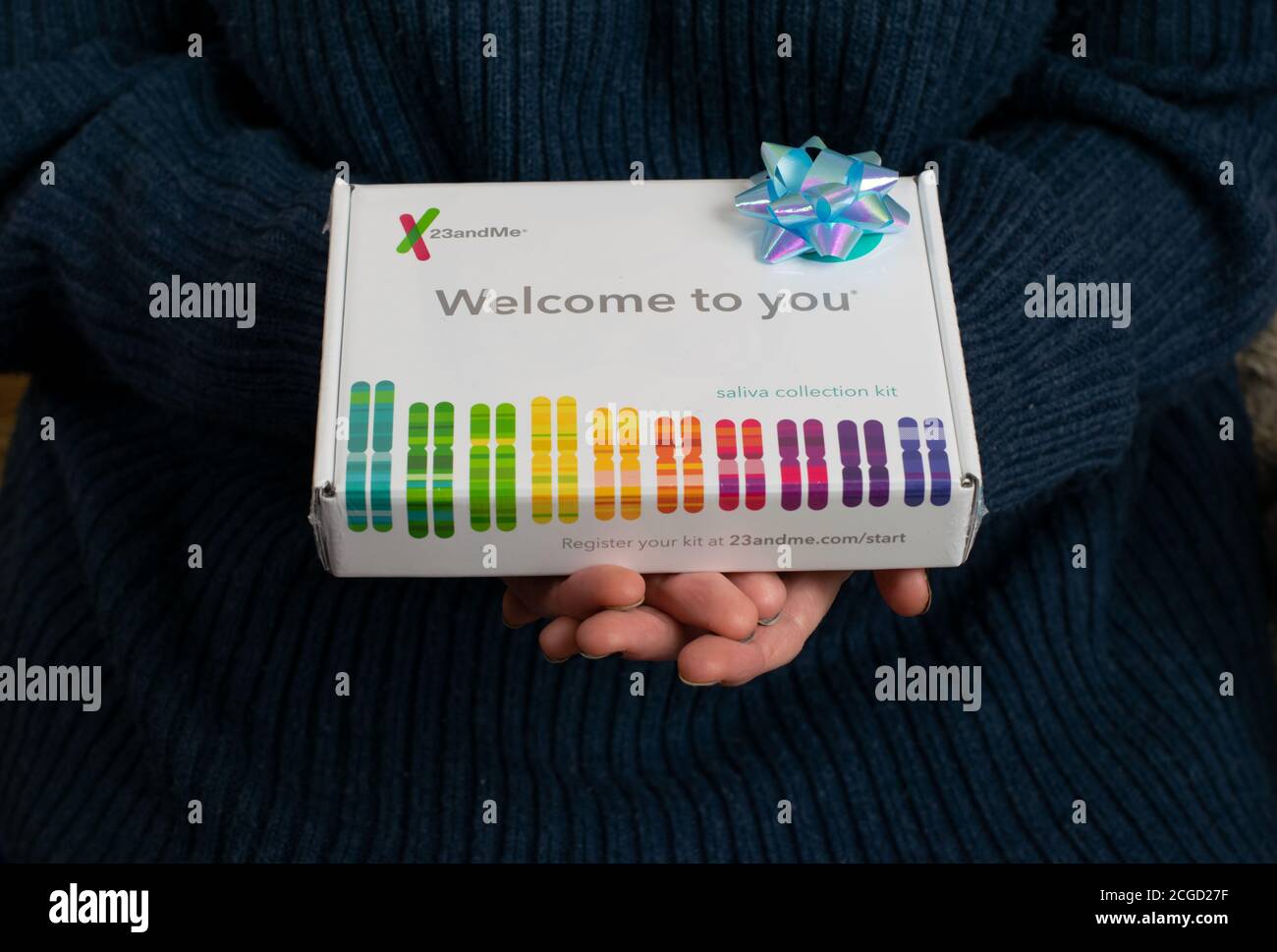 23 and me human DNA testing kit gift with blue gift bow held by two hands. Saliva sampling kit with text Welcome to You. Stock Photo