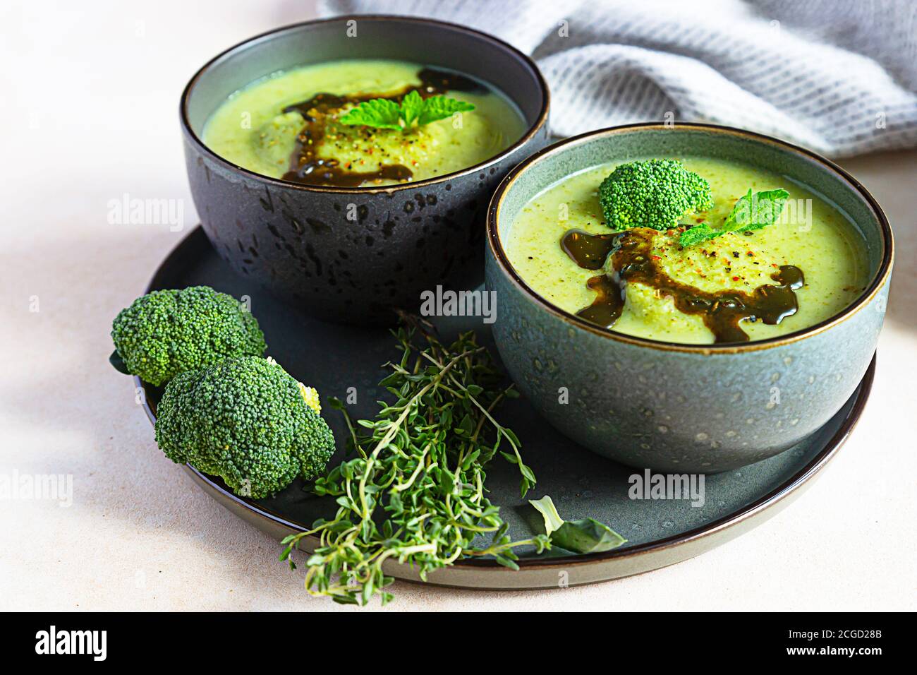 Broccoli or spinach green soup with aromatic spicy oil in bowl. Vegan healthy food. Stone background. Stock Photo