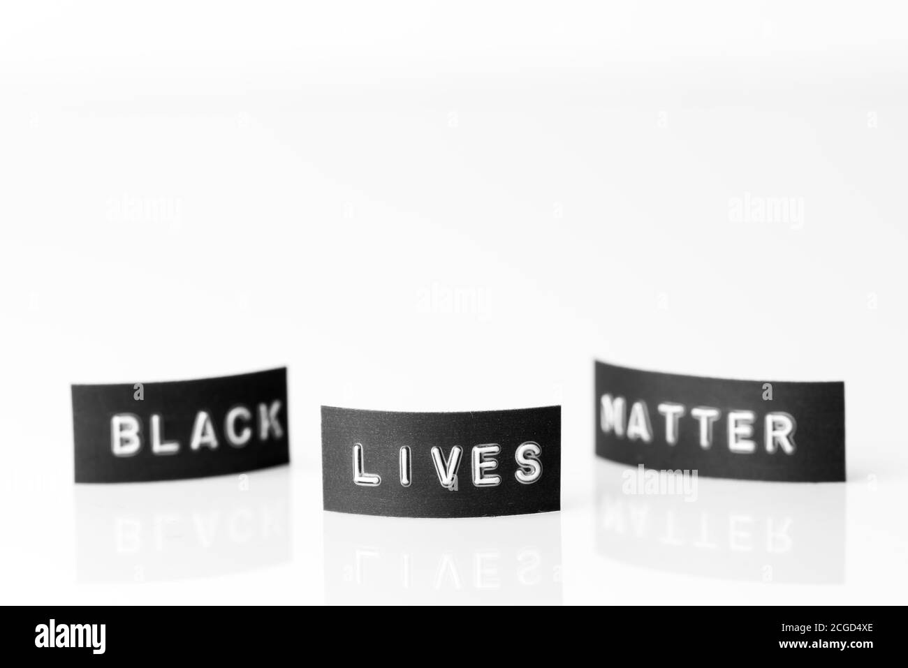 Slogan 'Black lives matter' written on small labels standing on white reflective plate Stock Photo