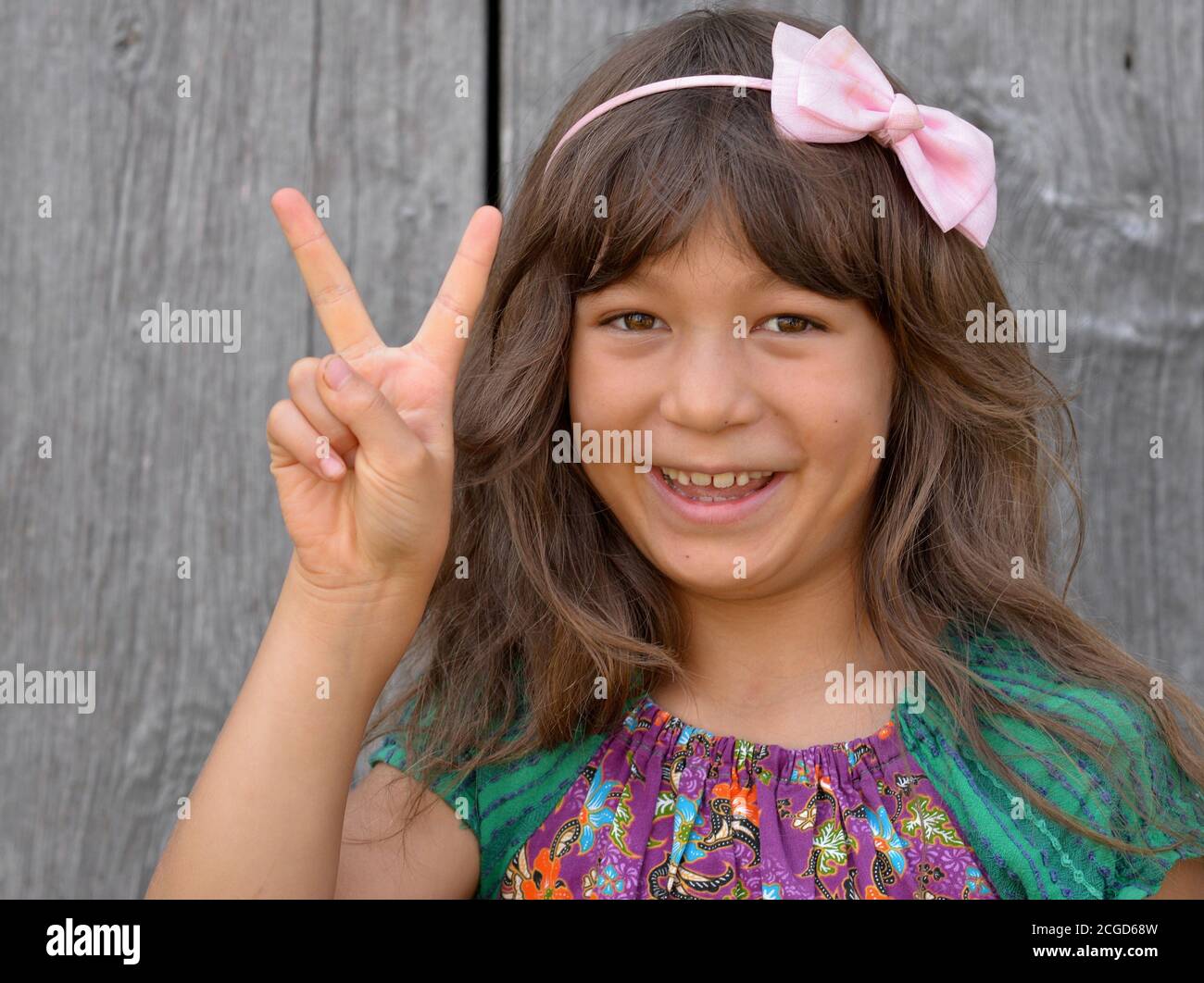 Cute mixed-race little girl (East Asian / Caucasian) shows with her right hand the Chinese hand sign for number 2 (photo series: image no. 2 of 10). Stock Photo