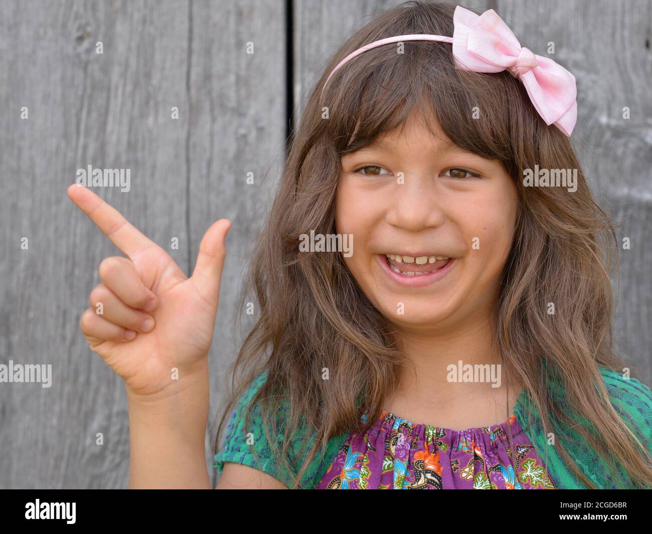 Cute mixed-race little girl (East Asian / Caucasian) shows with her right hand the Chinese hand sign for number 8 (photo series: image no. 8 of 10). Stock Photo