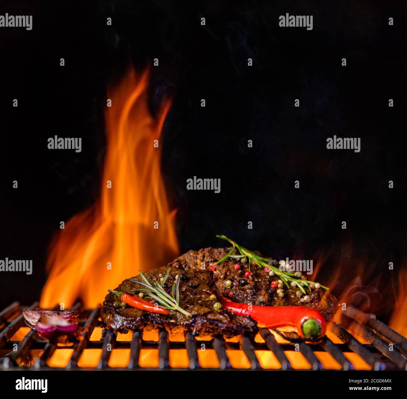 Beef steaks on the grill grate, flames on background. Barbecue and grill, delicious food. Stock Photo