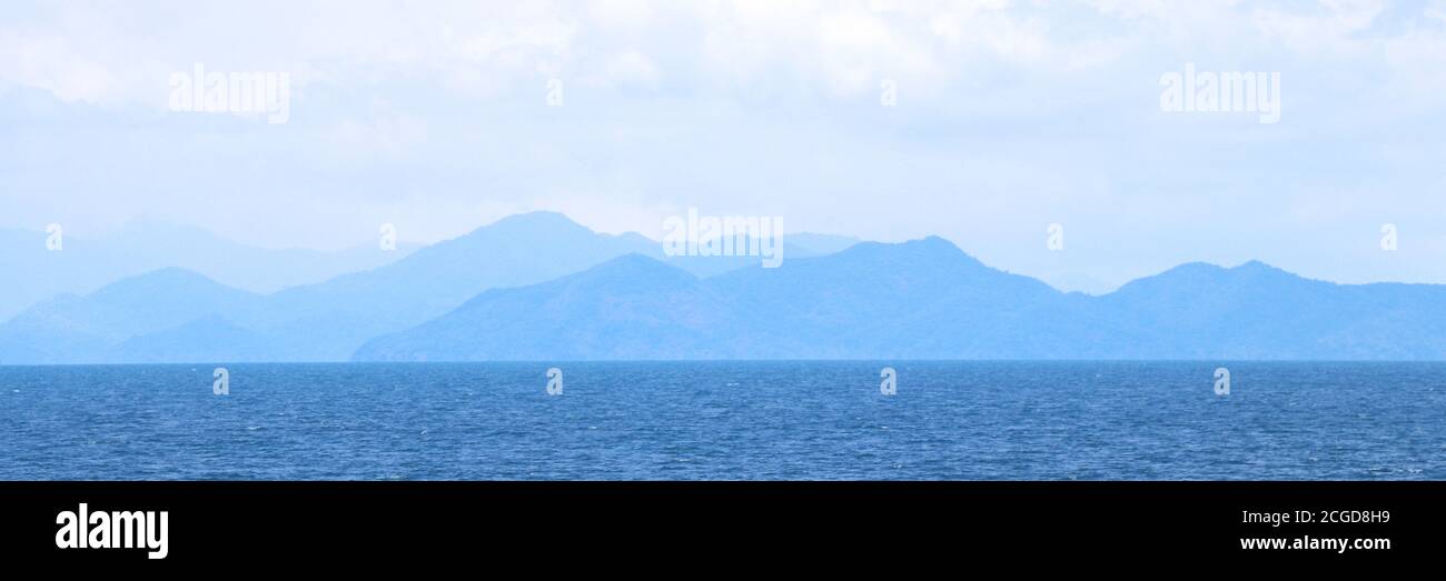 Blue sea with mountains and sky banner background. Stock Photo