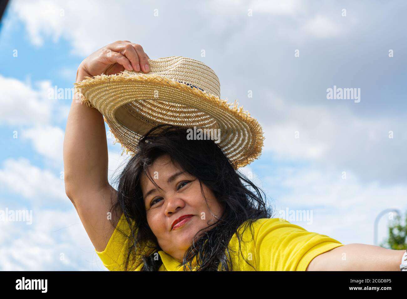 A middle-aged Asian woman, in her 50s, with a straw hat.  Stock Photo