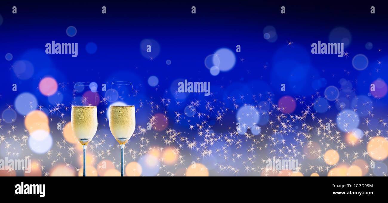Two glasses of chilled champagne on a shimmering blurred lights, blue background. Stock Photo