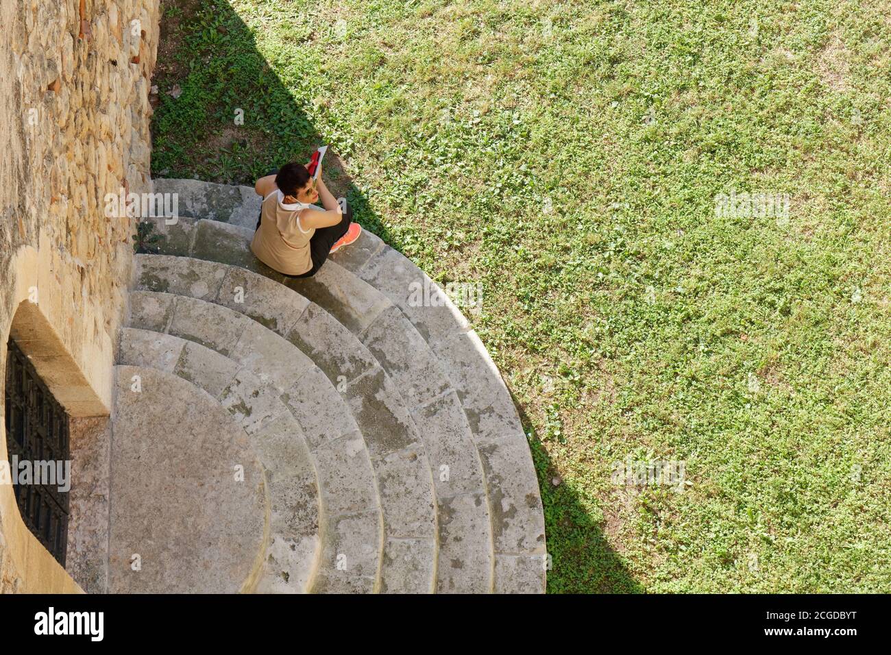 Above view of a woman sitting on the steps in the exterior of the castle of Soave, Italy Stock Photo