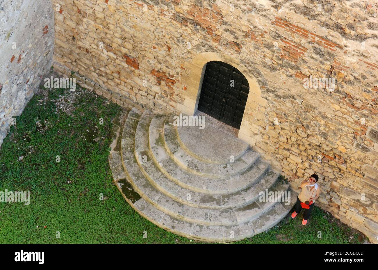 Above view of a woman greeting next to a portal of the castle of Soave, Italy Stock Photo