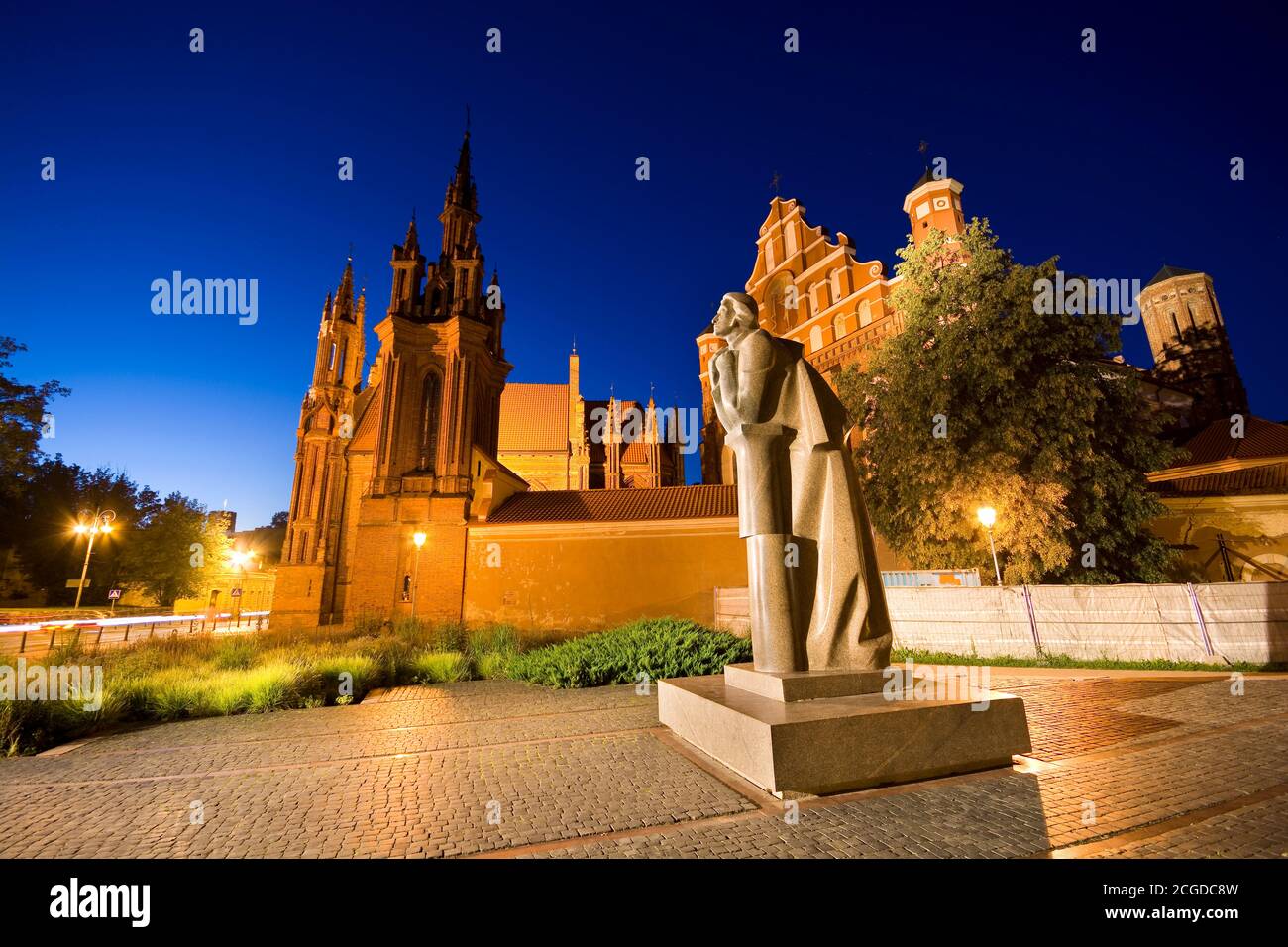 Night view of illuminated Mickiewicz statue at Maironio Street in the Old Town of Vilnius, Lithuania. Gothic style St. Anne Church and St. Francis and Stock Photo