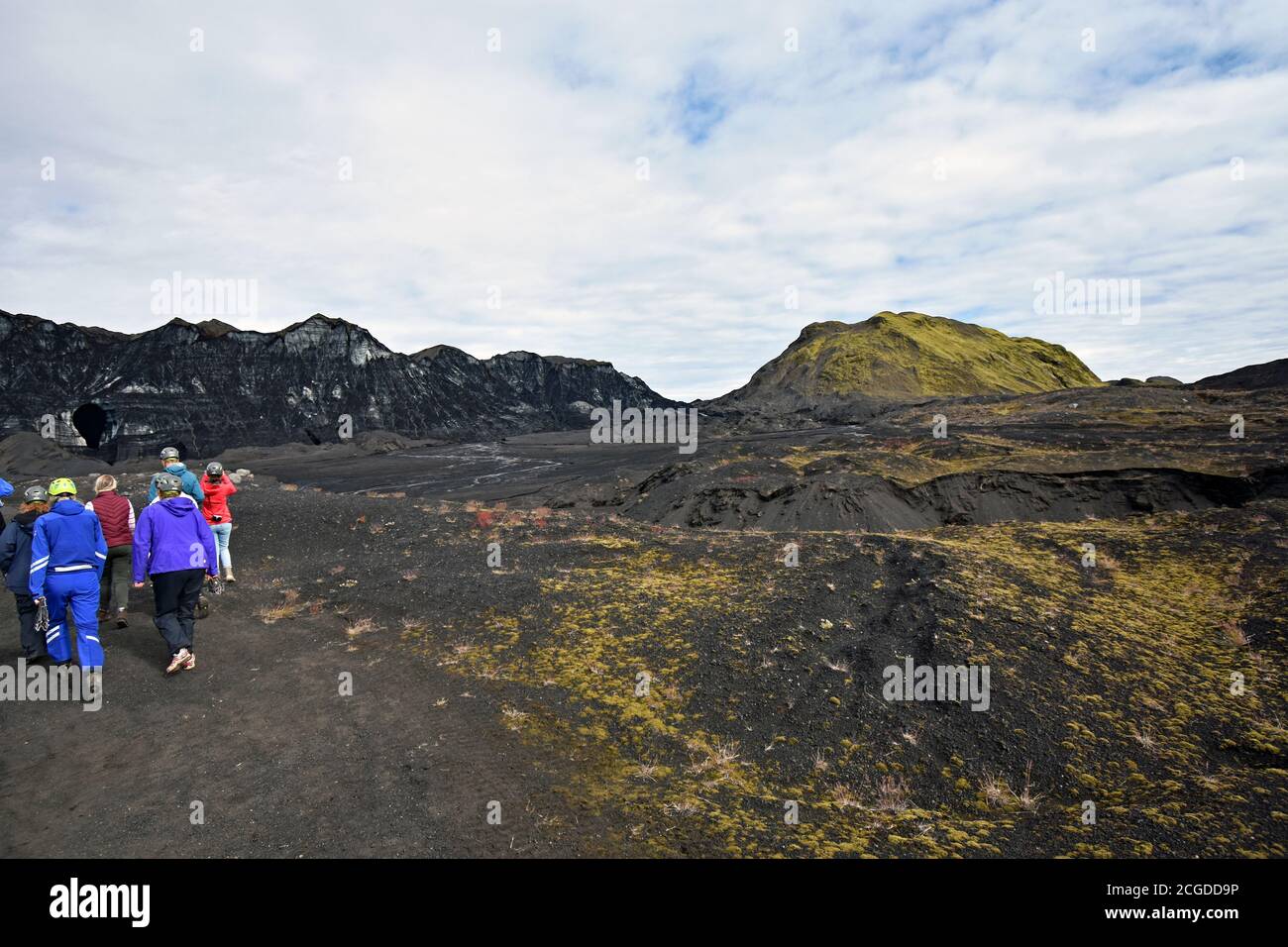 A tourist group in brightly coloured clothing contrast with the black volcanic sand glacial outwash plain for the Kotlujokull Glacier. South Iceland Stock Photo