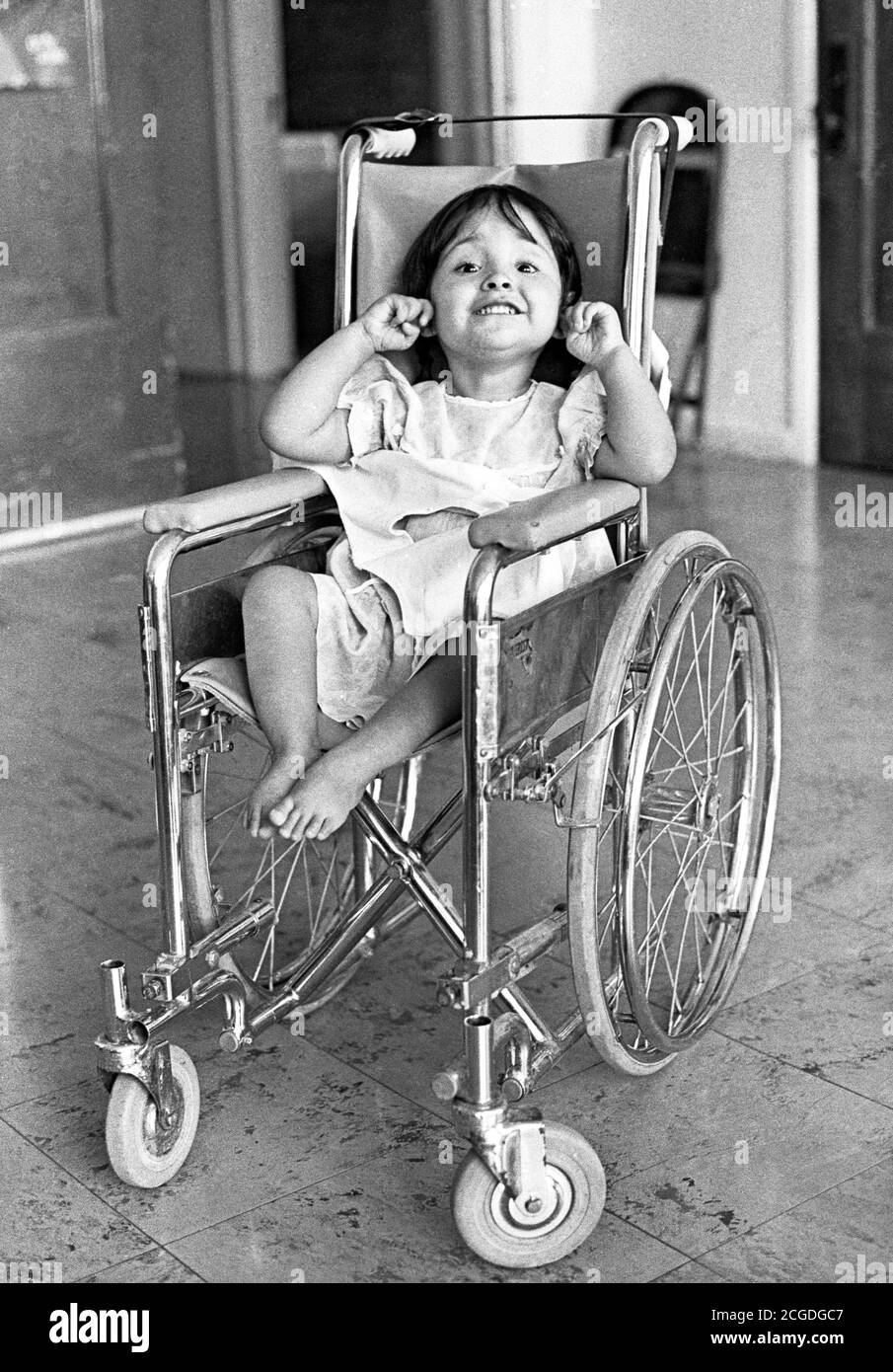 A little girl in her wheelchair at a hospital for crippled children  in New Mexico greets the world with a smile. Stock Photo