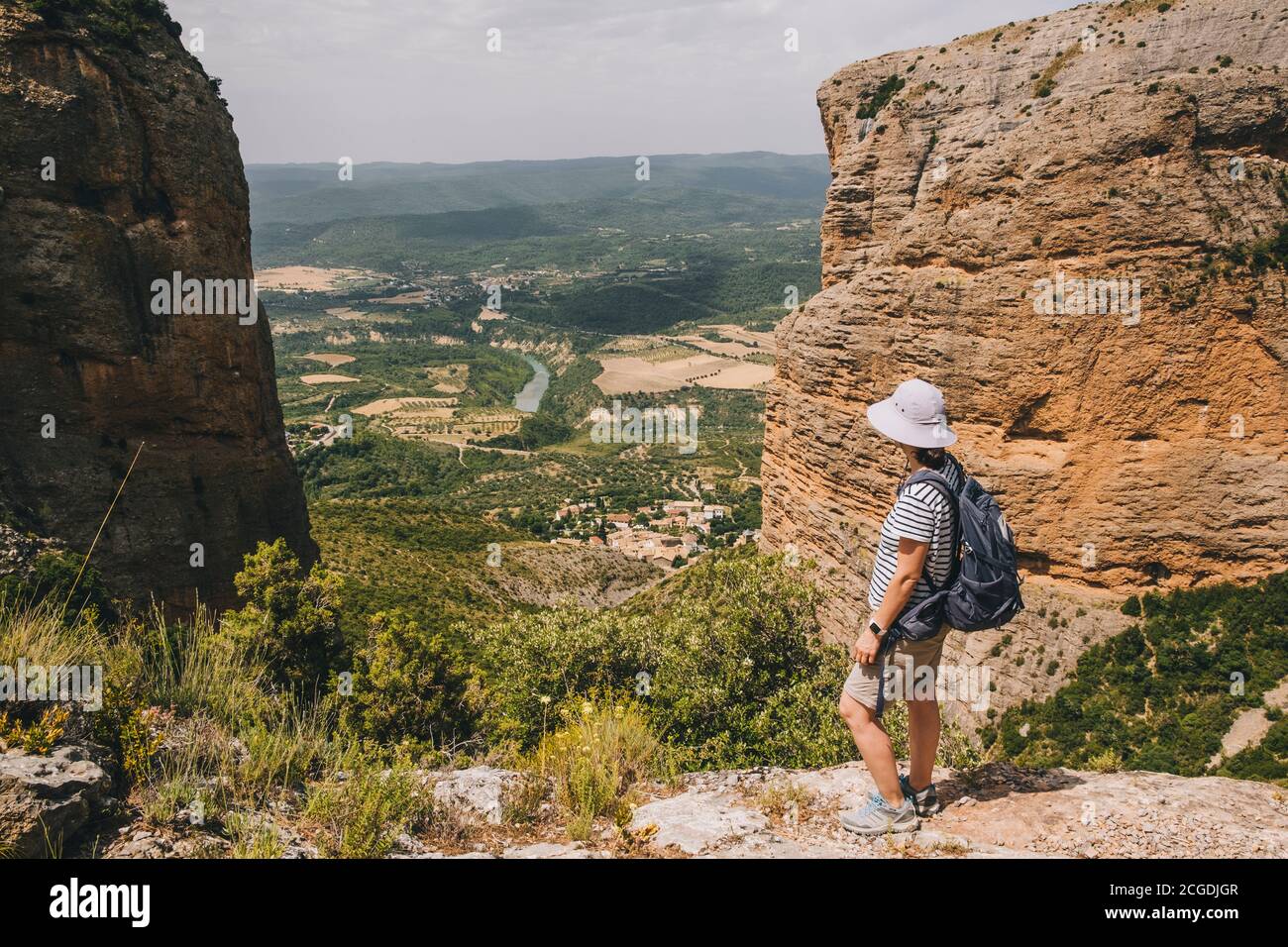 A young athletic woman stops at a viewpoint along the Mallos de Riglos circle route, The Pyrenees, Huesca, Aragon, Spain Stock Photo