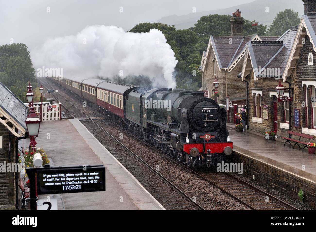 In pouring rain steam loco 'Royal Scot' with 'The Fellsman' special train passes Settle Station on the Settle-Carlisle railway line, North Yorkshire. Stock Photo