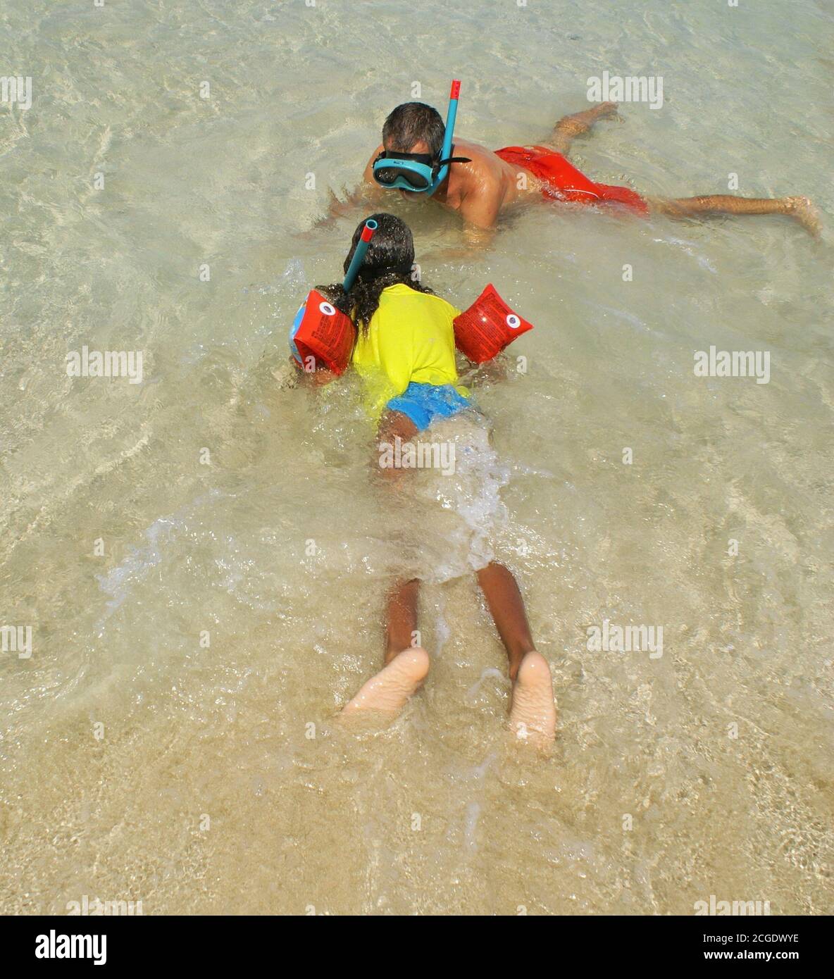 Multiracial family of father and his daughther playing and teaching  to do snorkel diving  at the border of the beach Stock Photo