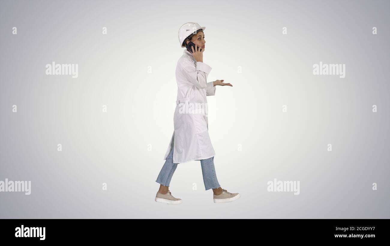 Female scientist making a call walking on gradient background. Stock Photo