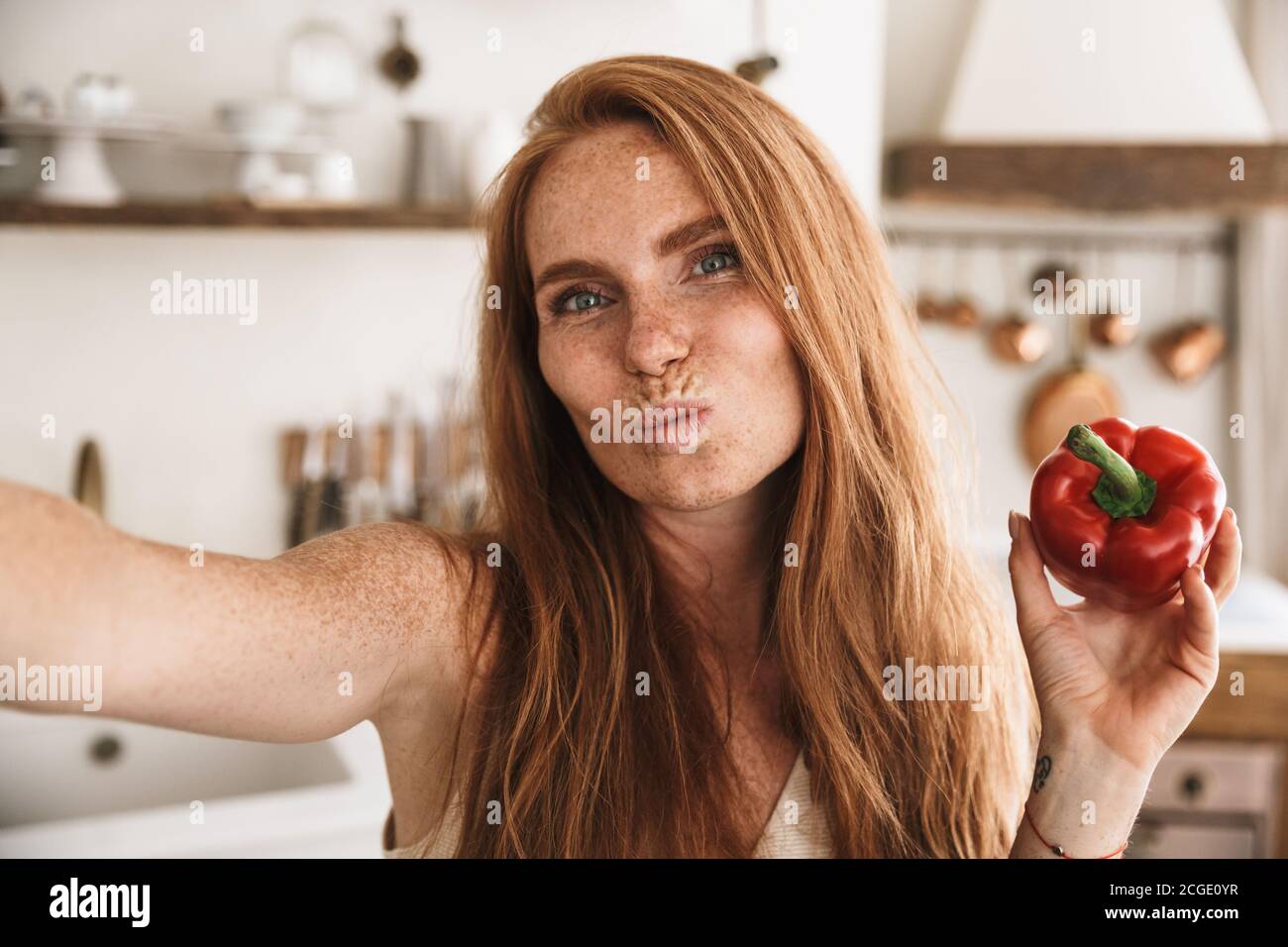 Image Of Happy Ginger Woman Taking Selfie Photo And Making Kiss Lips While Cooking At Cozy 