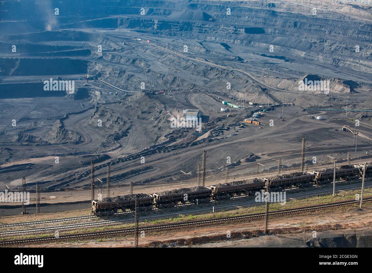 Open pit extraction and transportation of coal in quarry 'Bogatyr', Ekibastuz, Kazakhstan. Quarry machine and cargo train on railroad. Stock Photo