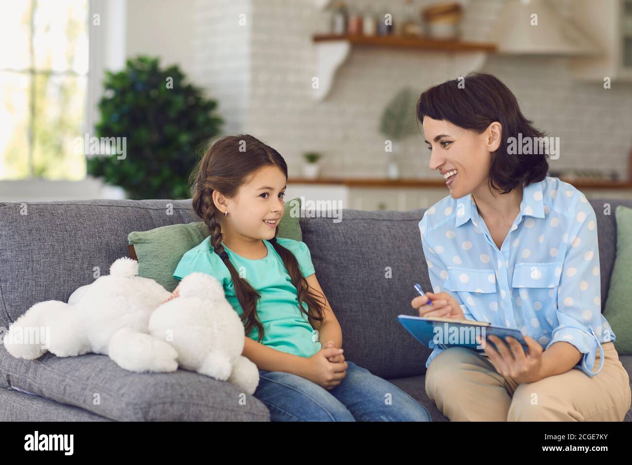 Smiling little girl talks to a cheerful child psychotherapist during a therapy session in the office. Stock Photo