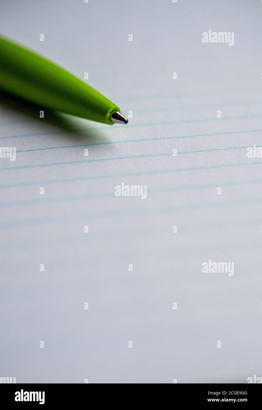 Green ballpoint pen on a lined notebook Stock Photo