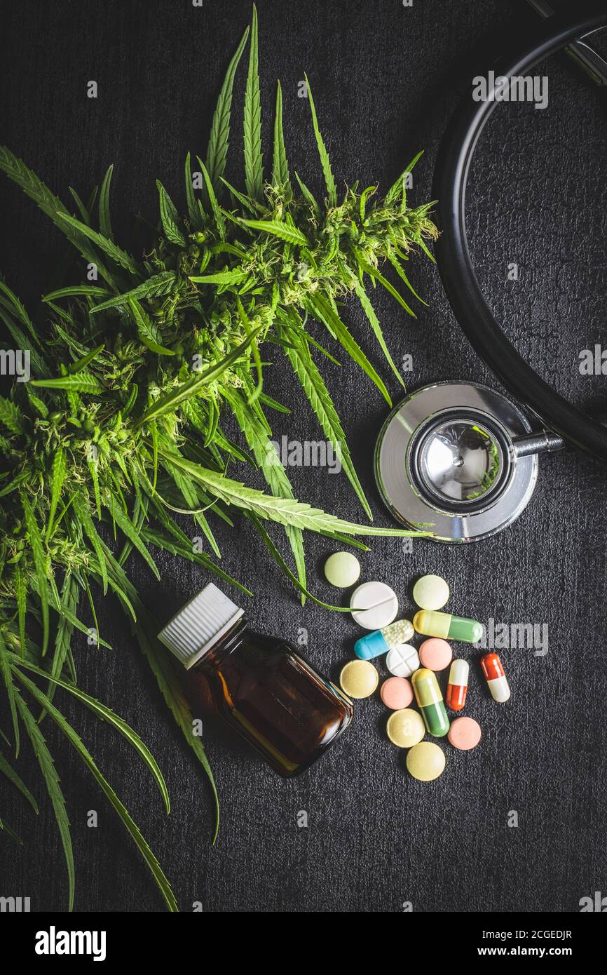 Marijuana buds flowers of cannabis, stethoscope,pills and oil on balck table. Top view. Stock Photo