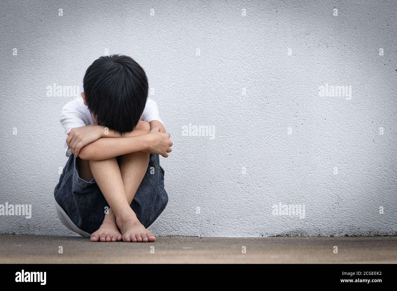 A boy sitting alone with sad feeling. Asian little child covered ...