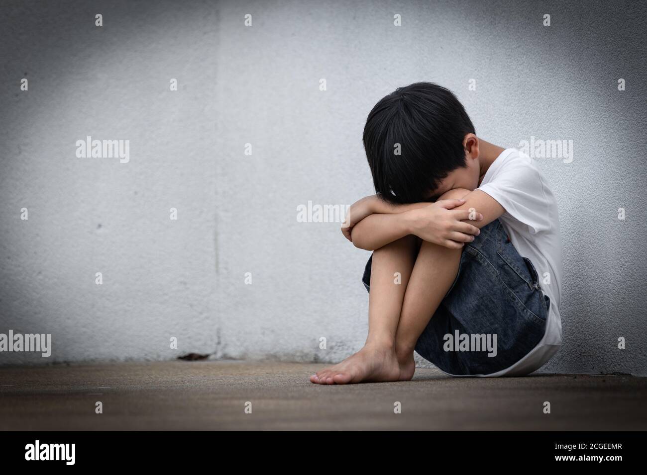 A boy sitting alone with sad feeling. Asian little child covered ...