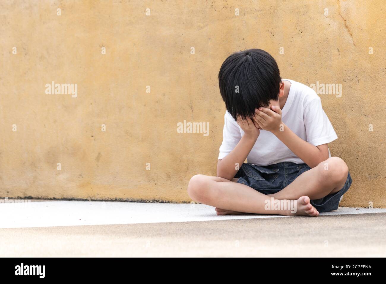 A boy sitting alone with sad feeling. Asian little child covered ...