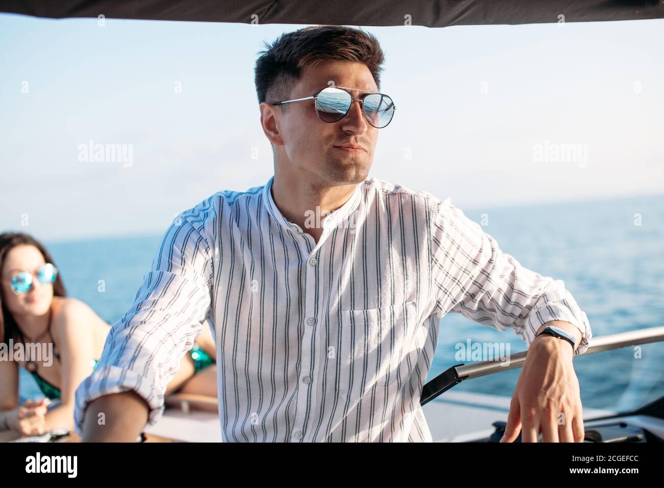 Confident caucasian business man with lether backpack handling an order over the phone and with his laptop while sailing on yacht trip at sea Stock Photo