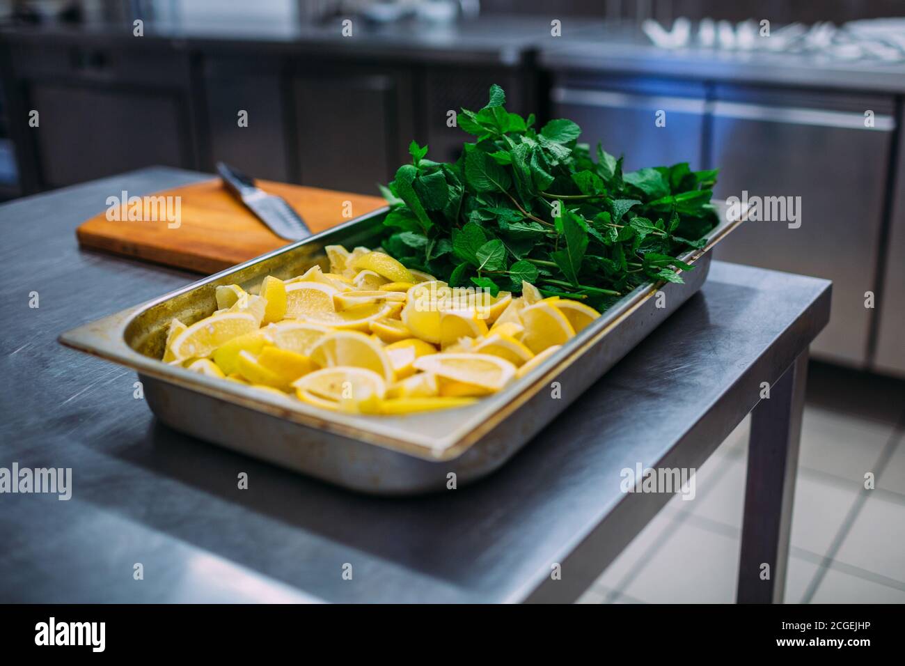 Preparing mojito ingredients in a restaurant kitchen. A lot of chopped lemon and mint. Stock Photo