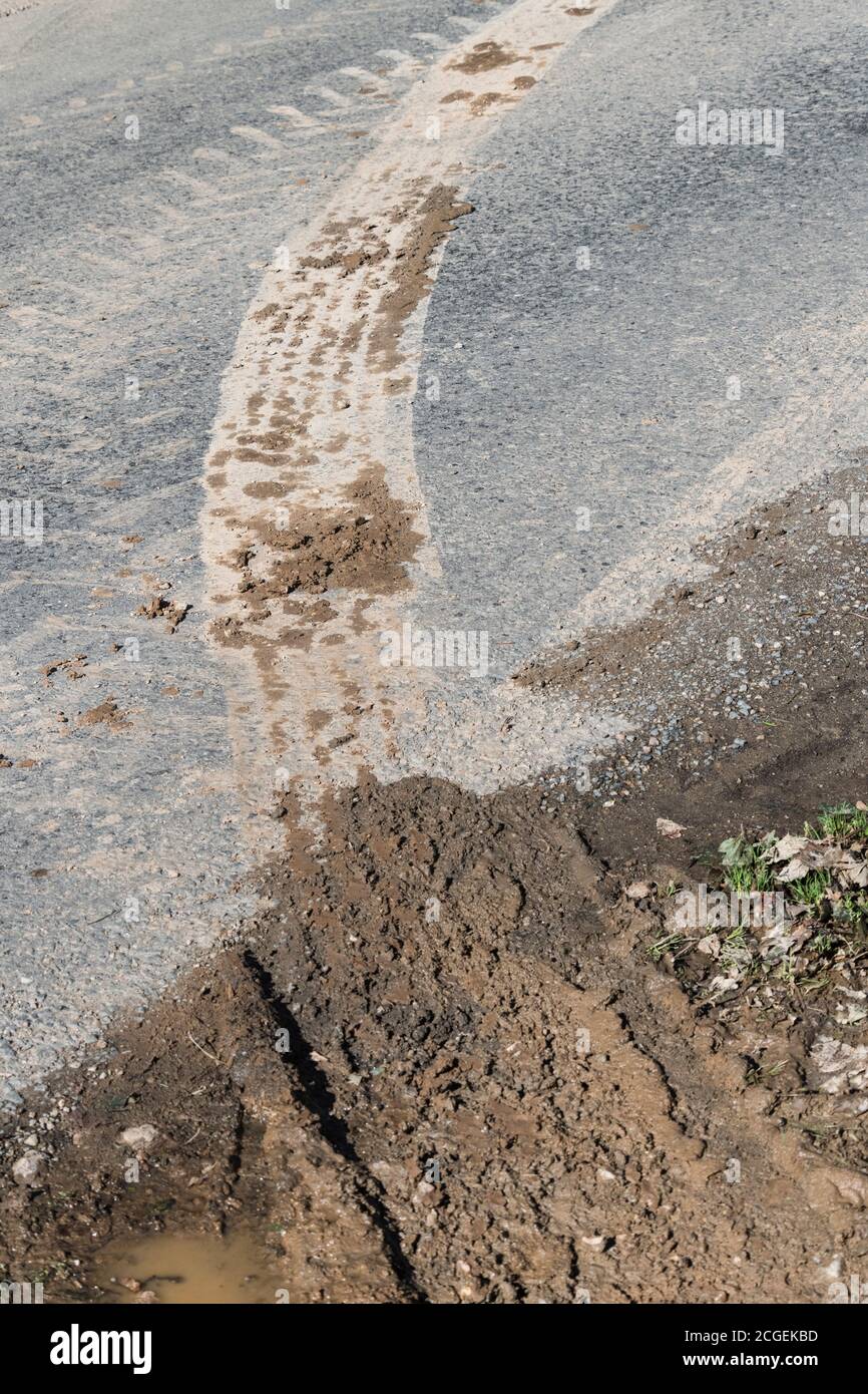 Muddy tyre marks of heavy farming machinery at the entrance to a field. For farm equipment, farming in UK, harvest time, all weather farming. Stock Photo