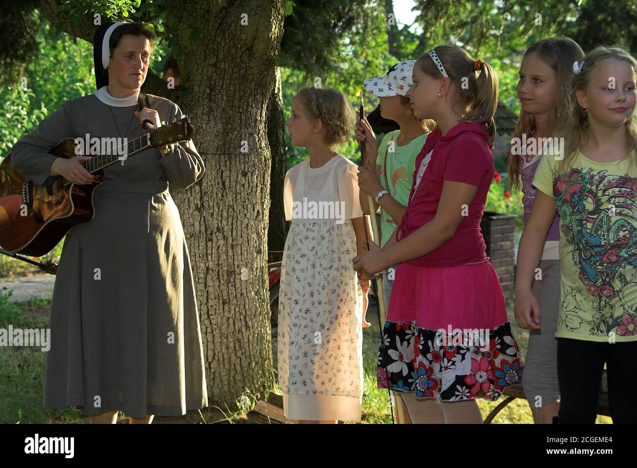 Poland A nun with a guitar surrounded by a group of school-age girls. Eine Nonne mit einer Gitarre, umgeben von einer Gruppe schulpflichtiger Mädchen. Stock Photo
