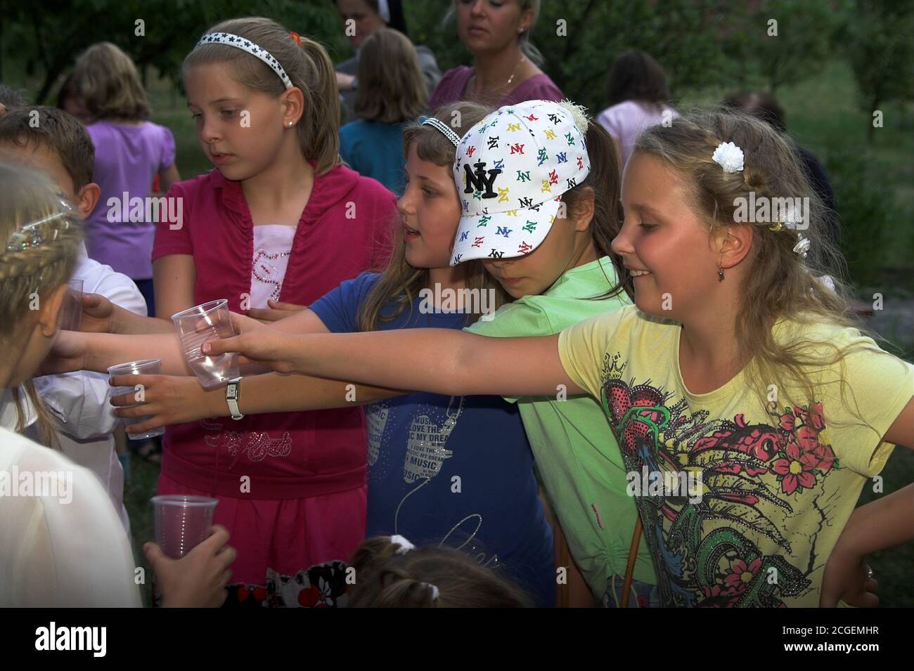 Poland Children at a picnic holding out their hands with cups for a drink. Kinder bei einem Picknick halten ihre Hände mit Tassen für einen Drink aus. Stock Photo