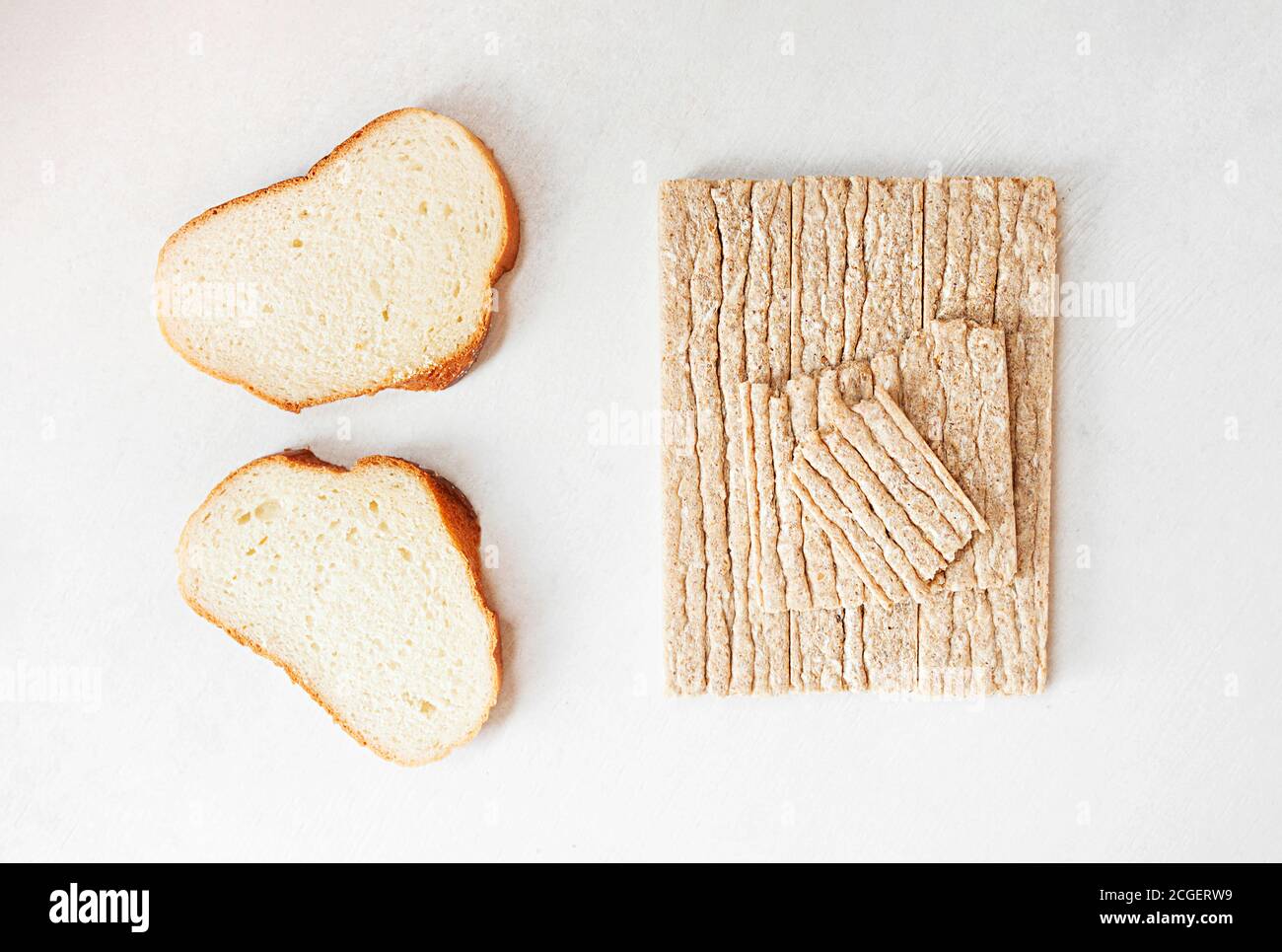 Different types of bread, white yeast bread and healthy crispbread on a white cement table, top view Stock Photo