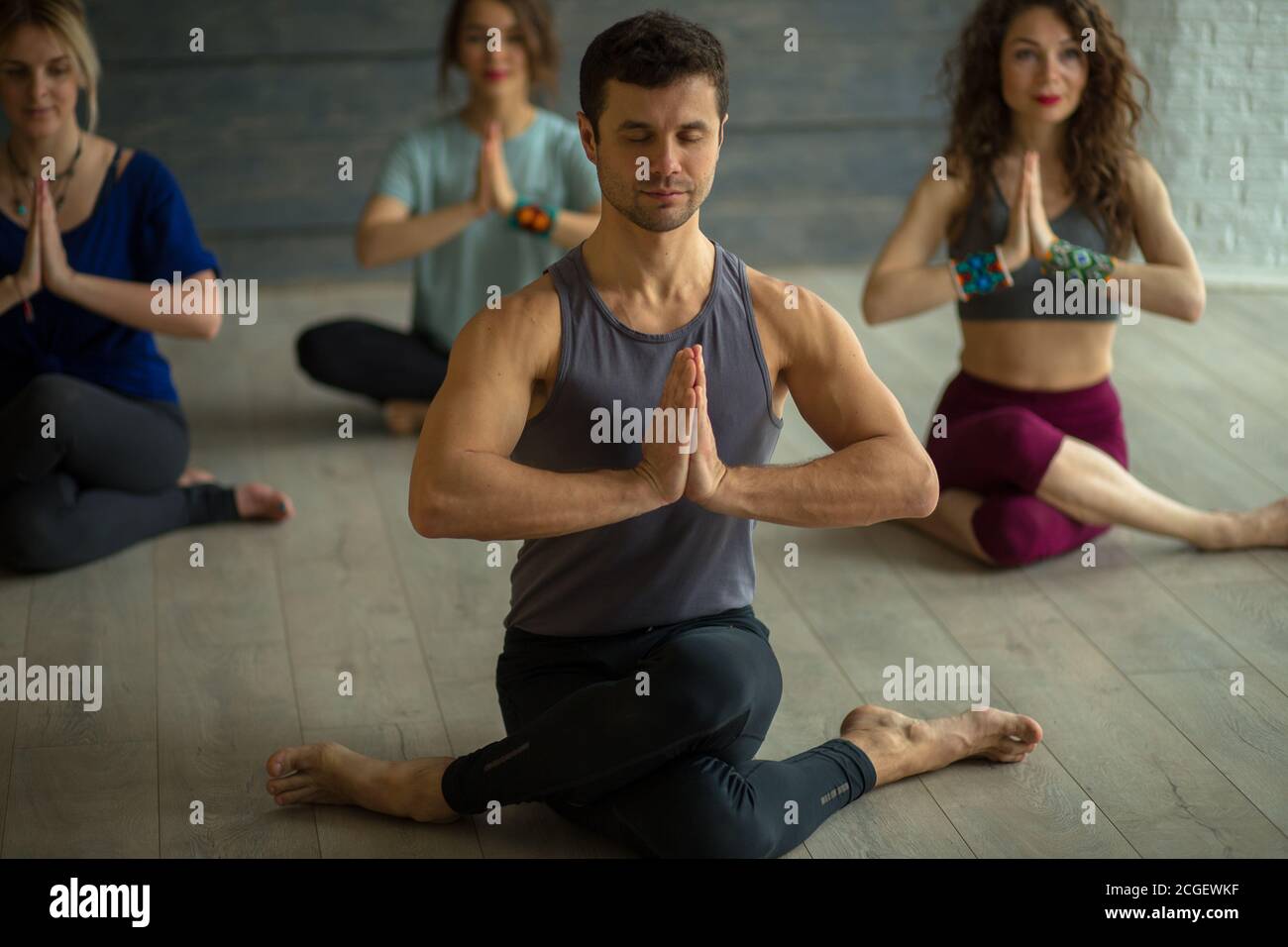 Kristopher Pace Positive athletic male Instructor taking yoga class in fitness studio ...