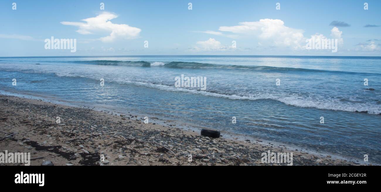 Caribbean Sea waves flowing into a Frederiksted Beach under a blue sky with clouds on St. Croix in the US Virgin Islands Stock Photo