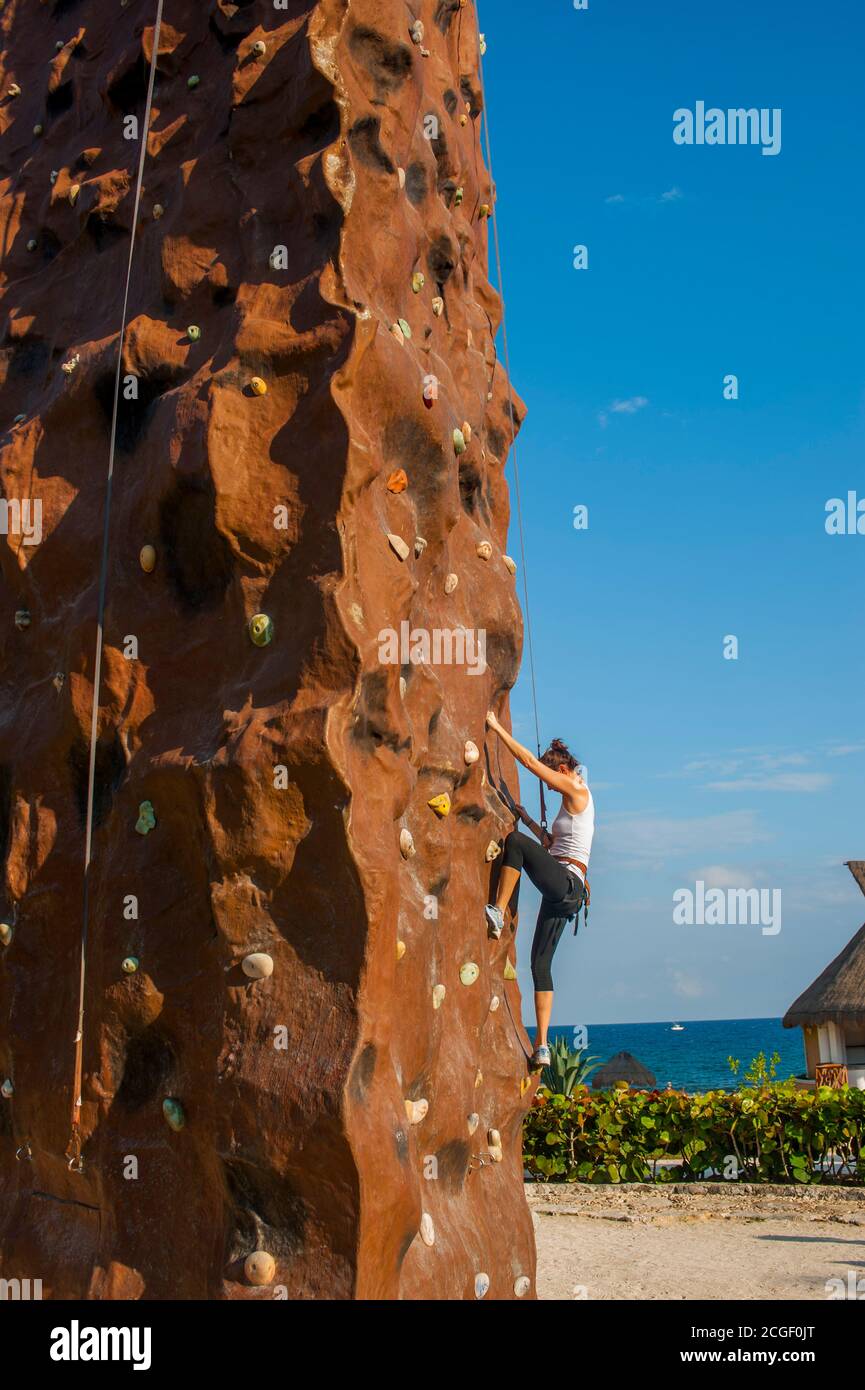 A woman is climbing on the climbing wall at the Hard Rock Riviera Maya