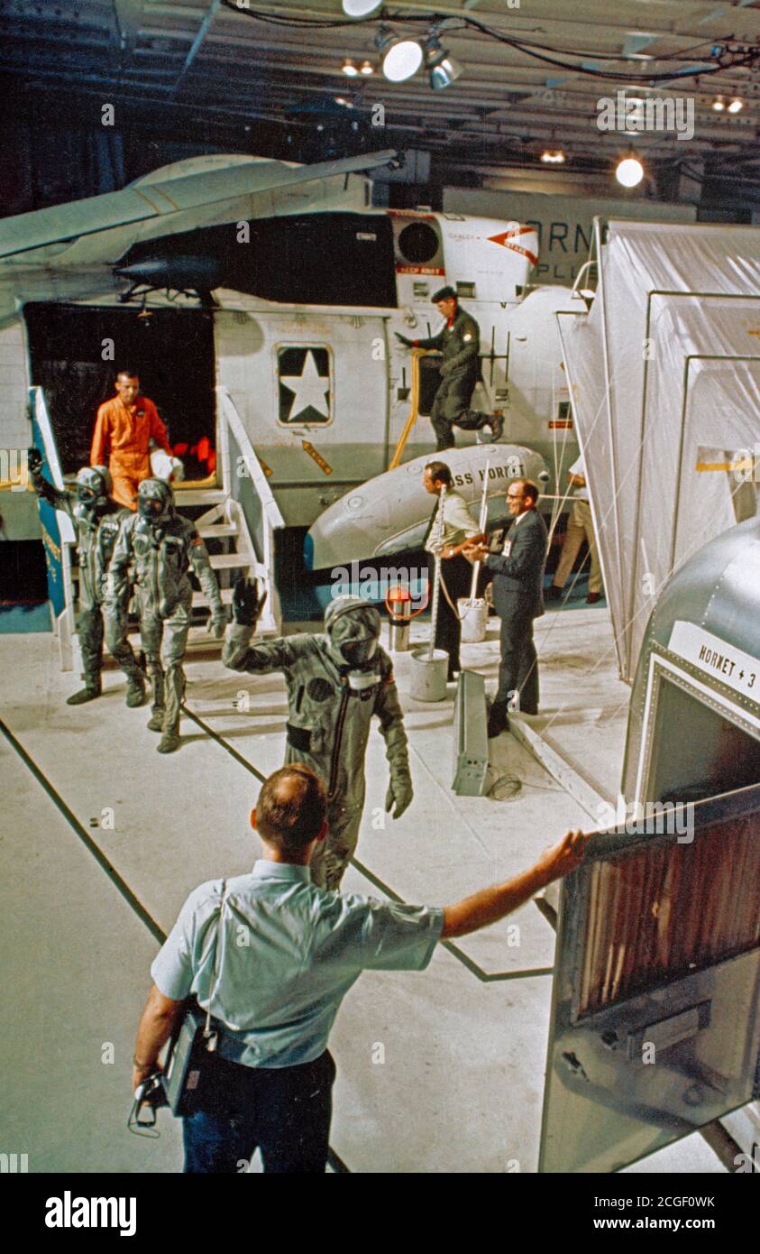 (24 July 1969) --- The Apollo 11 crewmen, wearing biological isolation garments, arrive aboard the USS Hornet during recovery operations in the central Pacific. They are walking toward the Mobile Quarantine Facility (MQF), in which they will be confined until they arrive at the Manned Spacecraft Center's (MSC), Lunar Receiving Laboratory (LRL). Stock Photo