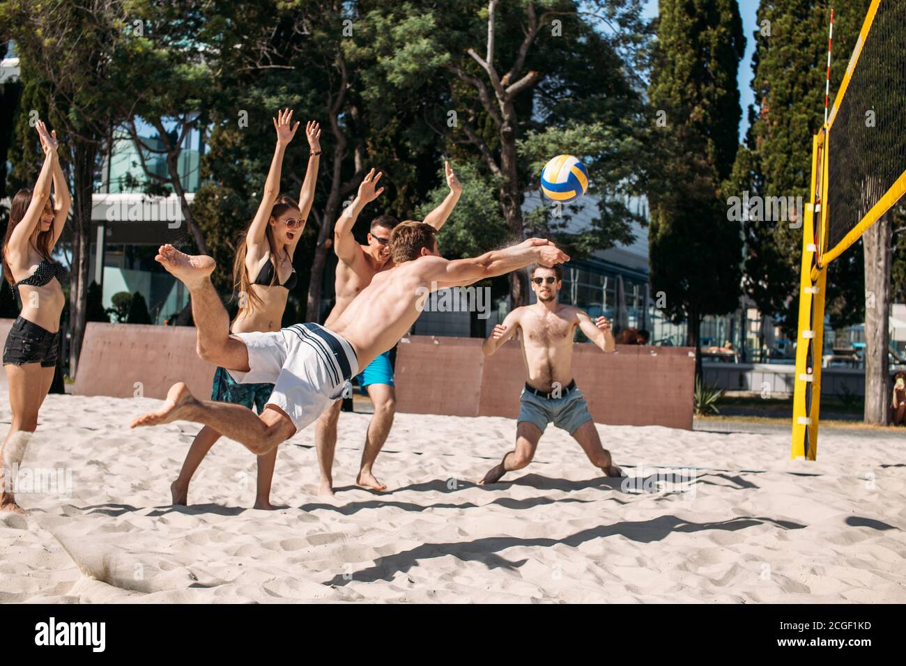 Fit, strong, healthy women and men doing sport on beach. Beach volleyball  at vacation leisuretime. Moment when man player with total body stretching  o Stock Photo - Alamy