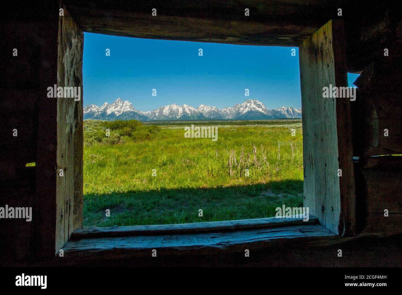 View of the Grand Teton Mountains through a window of the Cunningham Cabin (1888) in the Grand Teton National Park, Wyoming, United States. Stock Photo