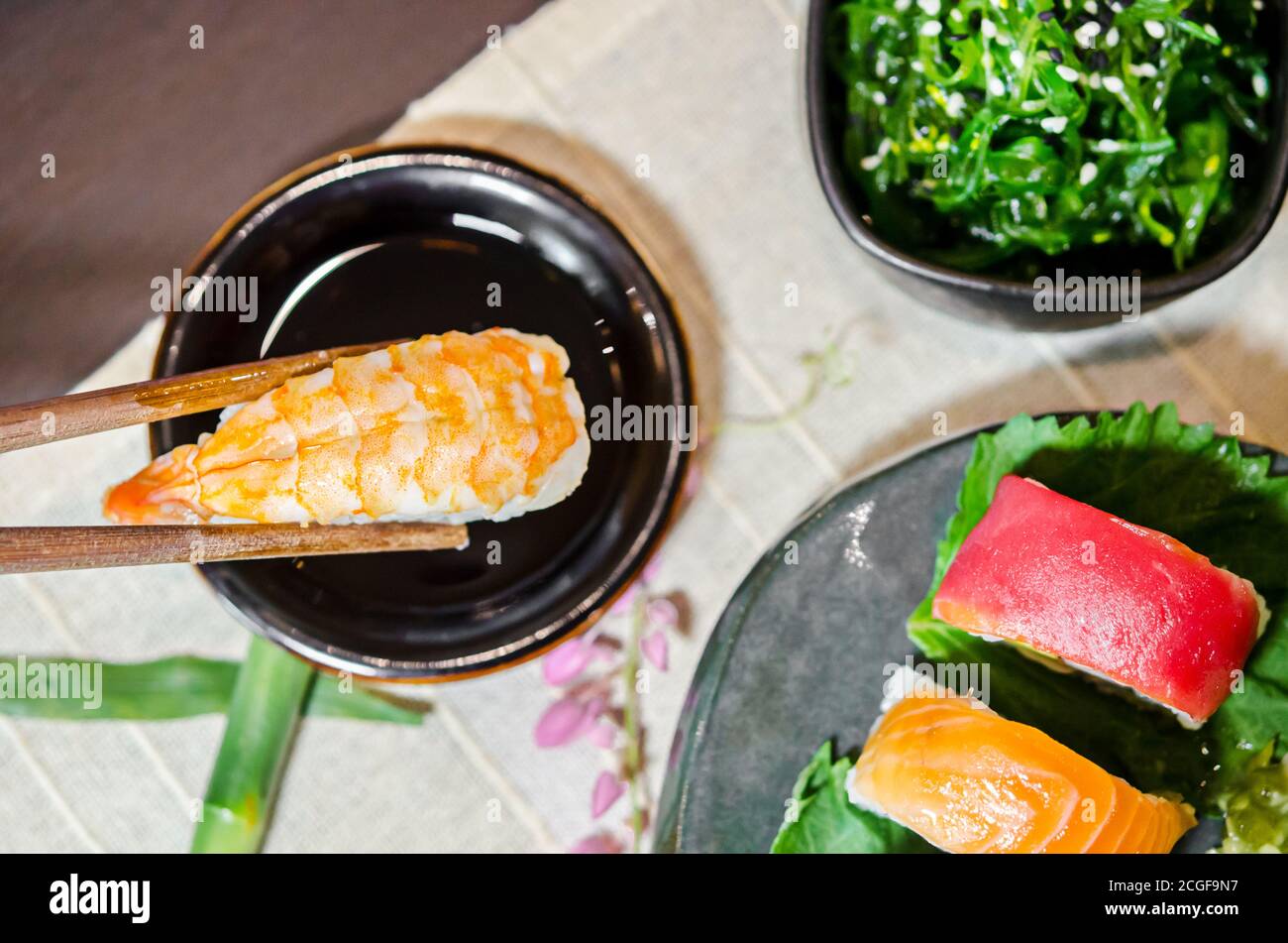 Hand holding wooden chopsticks tongs sushi at Japanese food restaurant