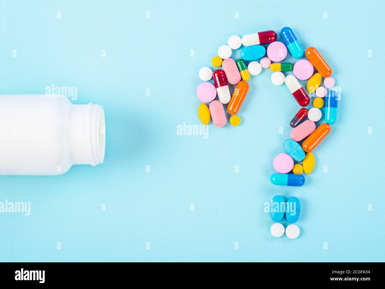 A question mark from laid out of medicine pills with bottle drug on blue background. Stock Photo