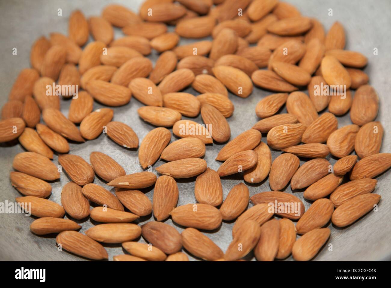 Closeup of roasting raw almonds with selective focus Stock Photo