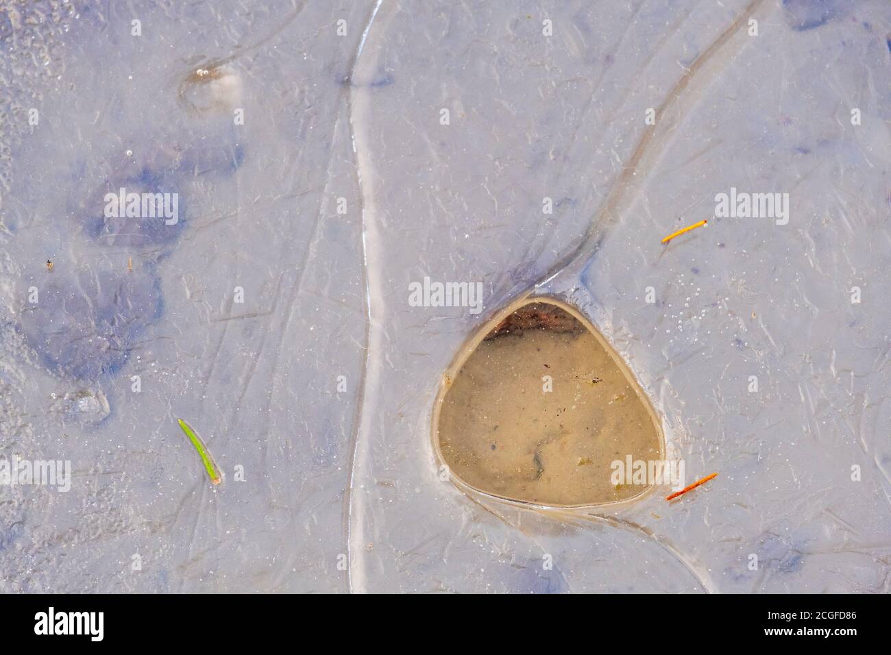 Thin ice with a hole on a beach Stock Photo