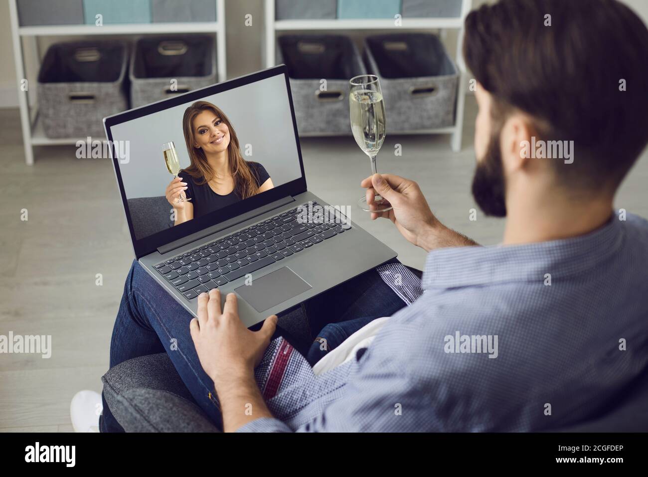 Online dating. Online meeting of a young man and woman. A man uses a video call, holds a glass of champagne and communicates with a beautiful woman. Stock Photo