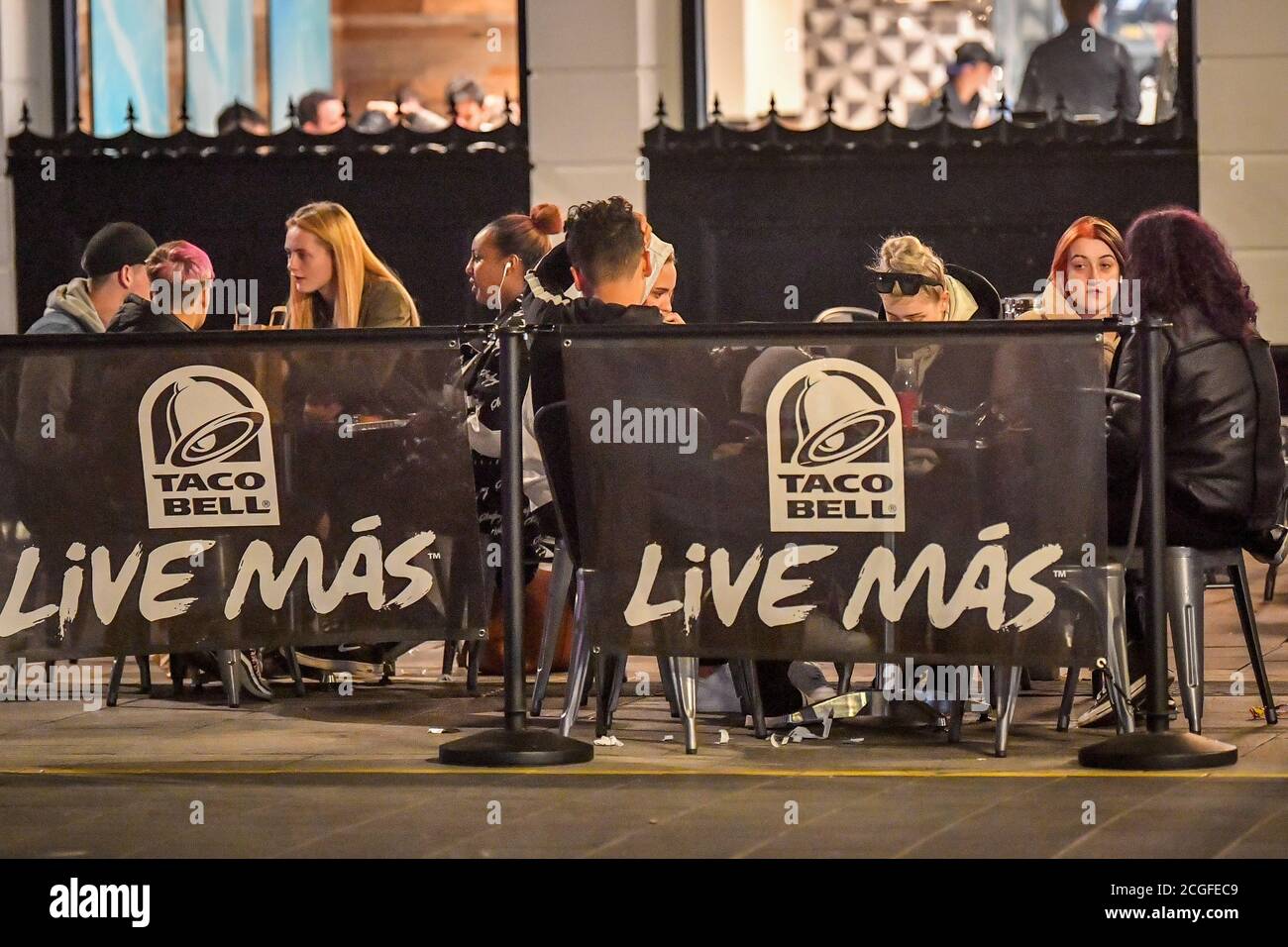 People outside a Taco Bell in Cardiff city centre at night. A ban on groups of more than six people meeting indoors in Wales, including pubs and restaurants, is expected to be announced later today as ministers try to tackle the rising number of coronavirus cases across the UK. Stock Photo