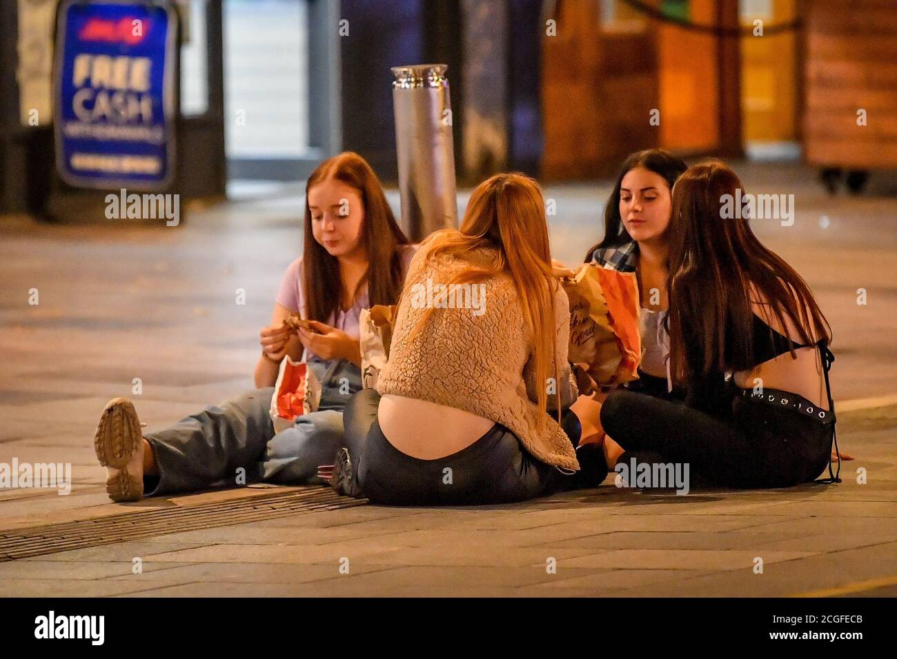 Young people eat take-away food in Cardiff city centre at night. A ban on groups of more than six people meeting indoors in Wales, including pubs and restaurants, is expected to be announced later today as ministers try to tackle the rising number of coronavirus cases across the UK. Stock Photo