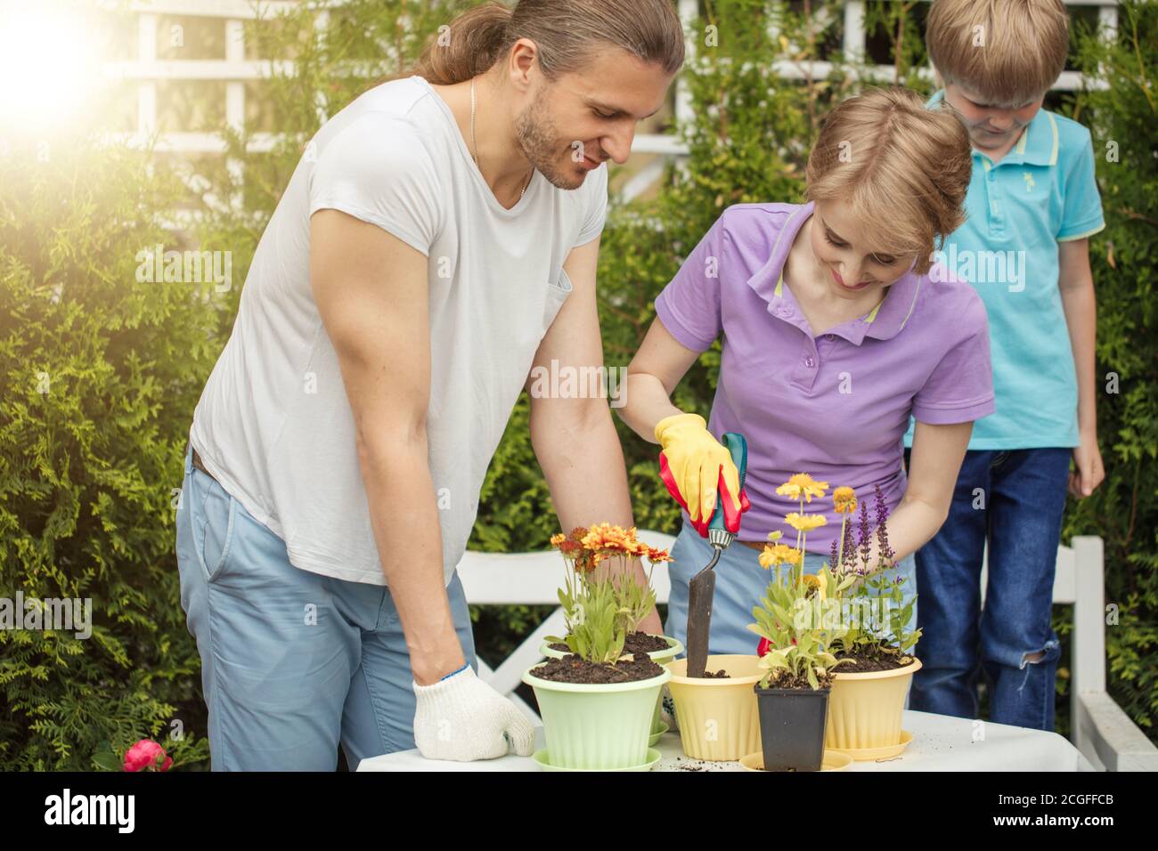 Parents Planting Planting flower. Gardening. Planting. Parents with son planting flower ...
