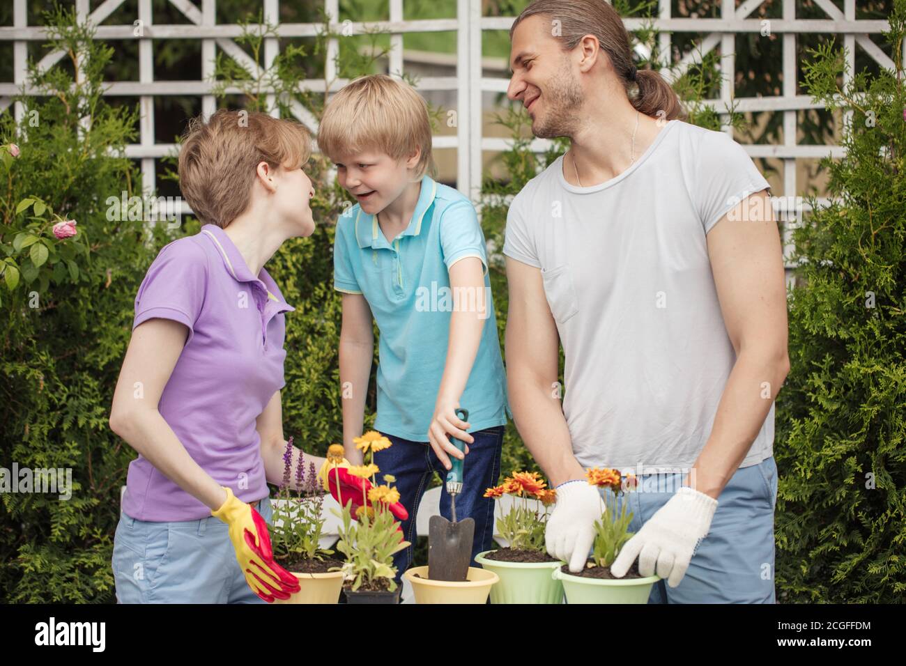 Parents Planting Boy kid helps parents planting flower in pot. Gardening, planting ...