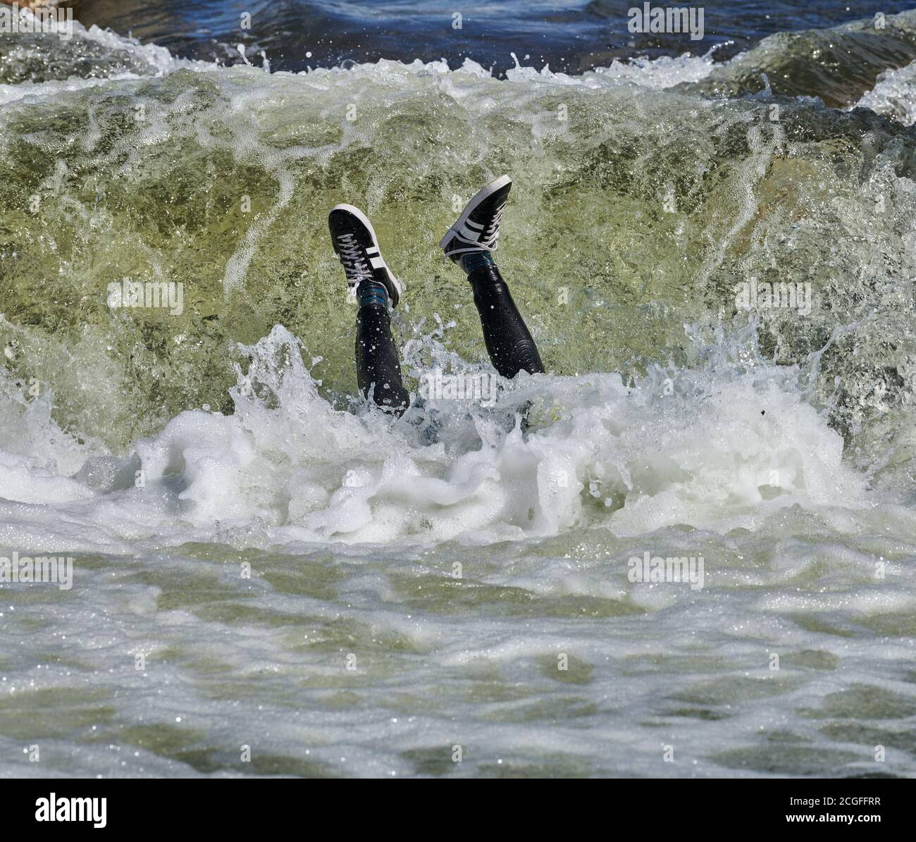 Teenage boy, with legs above water, disappears  into a stopper backwards on the artificial whitewater course at Northampton, England. Stock Photo