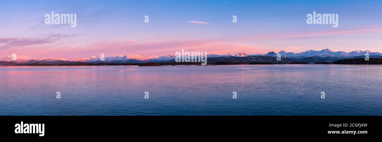 Panoramic vista of the coast of Norway with snow covered mountains in beautiful soft evening light Stock Photo